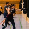 Frau mit Boxhandschuhen boxt Boxsack