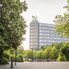 The photo shows the Math Tower on the TU-Dortmund campus surrounded by trees.