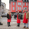 A woman and two men are standing in front of an intersection.