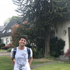 A man stands in front of a tree and houses and smiles at the camera