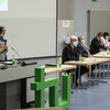 Several people with mouth-nose protection sit at tables in the Audimax, one person speaks