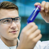 A researcher holds a sample vessel in his hand.