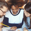 Three students put their heads together over documents.