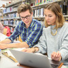 Three students sitting at the table in the library and working.